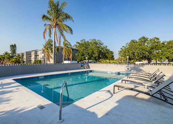 A pool with a diving board and sun loungers.
