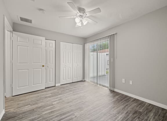 an empty living room with white doors and a ceiling fan