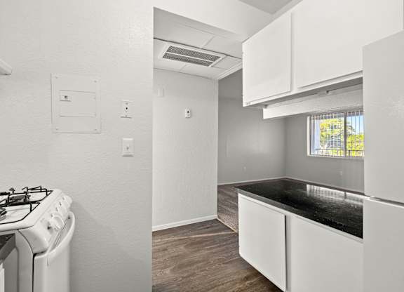 A kitchen with a stove, cabinets, and a window.