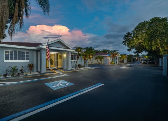 a street in front of a house with a flag and a cloudy sky