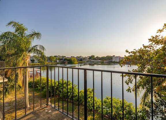 A balcony overlooks a body of water with a sunset in the background.
