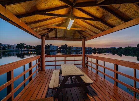 Picnic table on a wooden deck overlooking a body of water.
