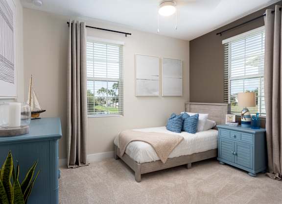 A bedroom with a bed, nightstand, and a plant.