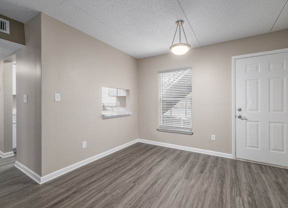 A room with a white door, a window with blinds, and a light hanging from the ceiling.