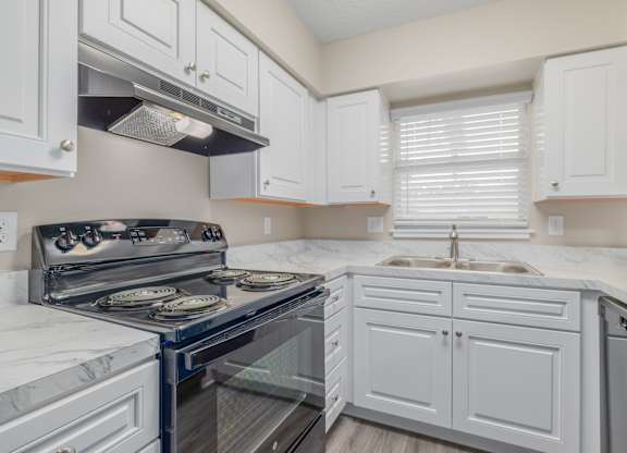 A kitchen with white cabinets and a black stove top.