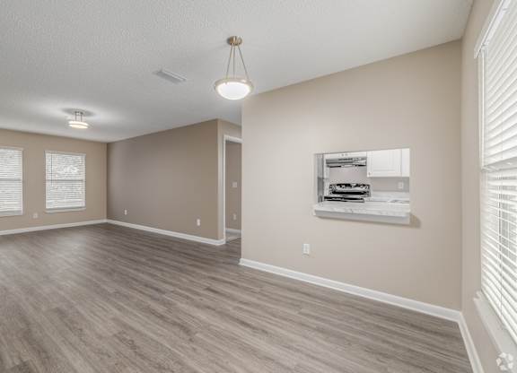 A room with a wooden floor and a window with blinds.