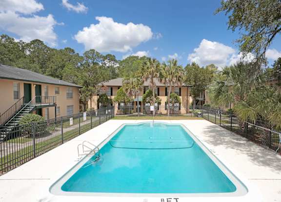 A swimming pool surrounded by a fence and trees.