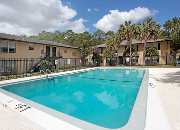 A swimming pool in a residential area with apartment buildings in the background.