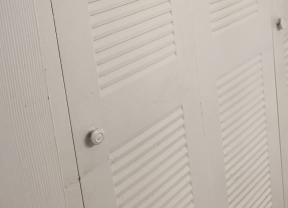 A white closet with a sliding door.