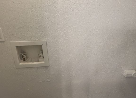 A white wall with a socket and a switch.