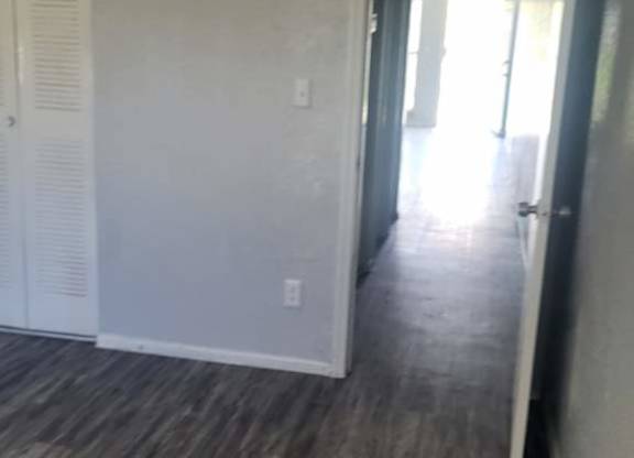 A room with a white door and a wooden floor.