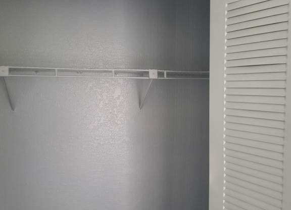 A wall with a shelf and a door with blinds.