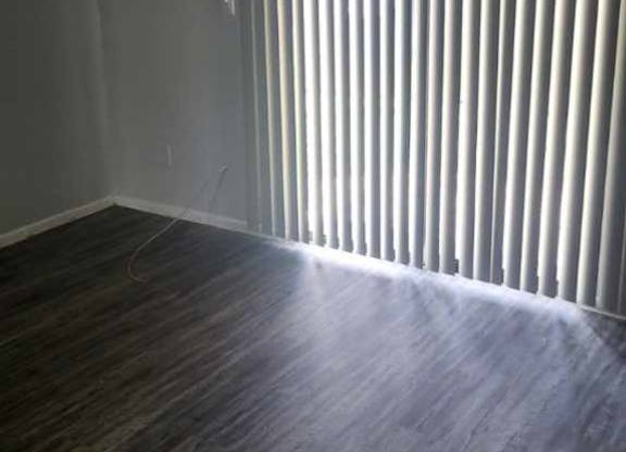 A room with a window covered by vertical blinds.