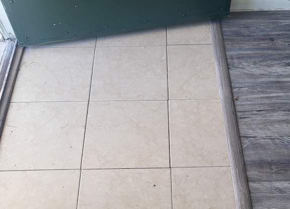 A white tile floor with a green door.