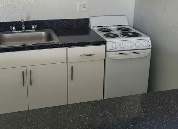 A kitchen with white cabinets and a black countertop.