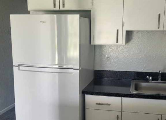A white refrigerator and cabinets in a kitchen.