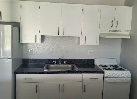 A kitchen with white cabinets and a stove top oven.