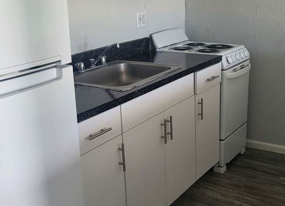 A kitchen with white cabinets and a black countertop.