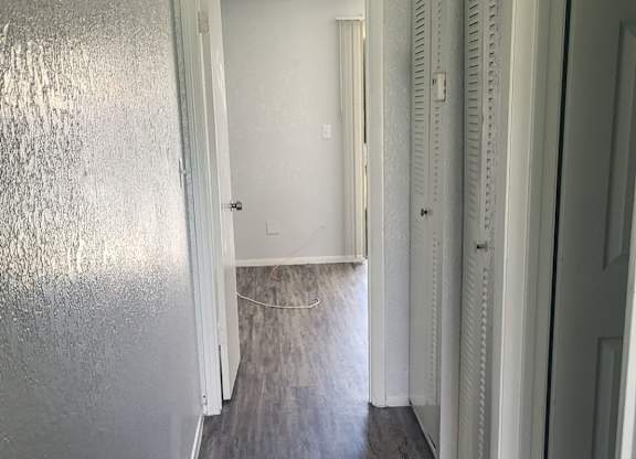 A long hallway with white doors and wood floors.