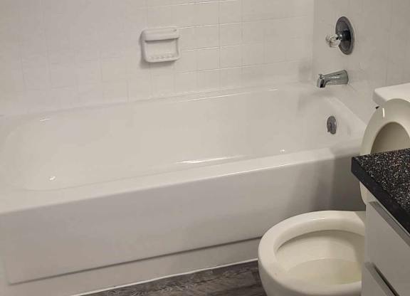 A white toilet in a bathroom with a white tiled wall.
