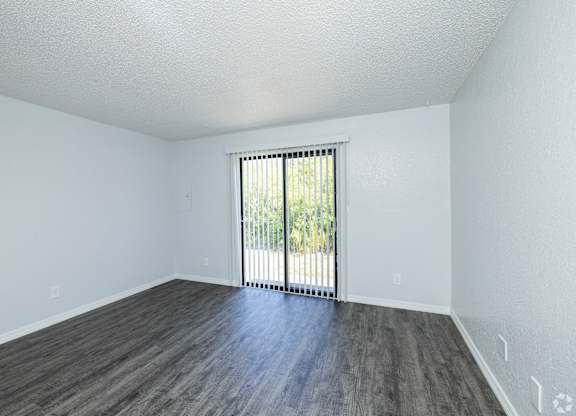A room with a sliding glass door and wooden flooring.