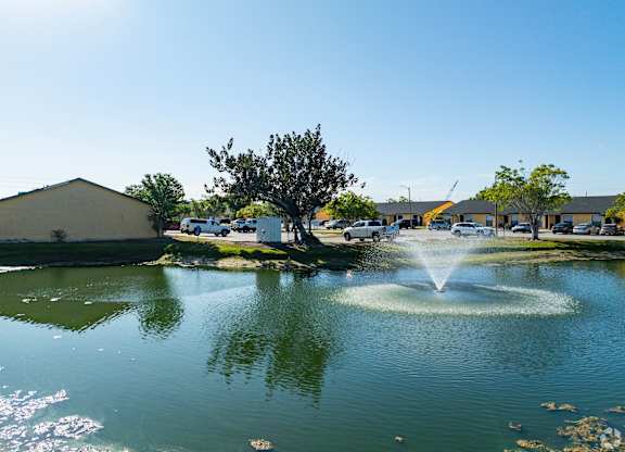 A fountain in the middle of a pond in a sunny day.