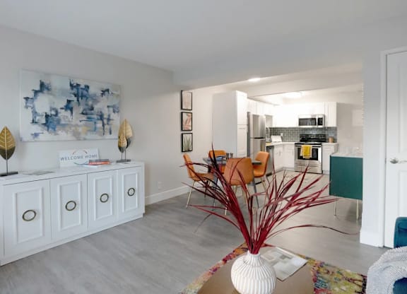 A white cabinet with a sign that says "Welcome" is in a room with a blue and white painting on the wall.