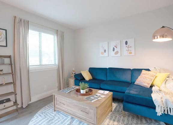 A living room with a blue couch and a wooden coffee table.