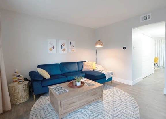 A living room with a blue couch and a wooden coffee table.