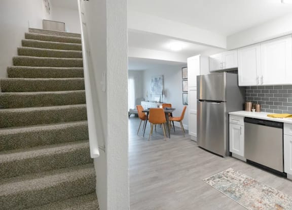 A kitchen with a refrigerator, stove, and chairs.