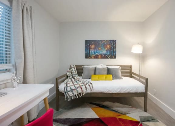 A bedroom with a bed, a desk, and a chair.