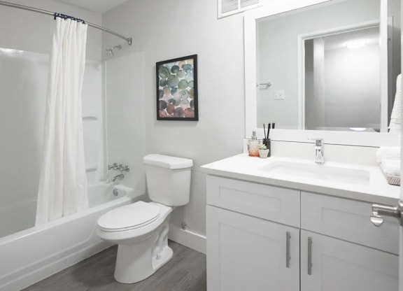 A white bathroom with a toilet, sink, and shower.