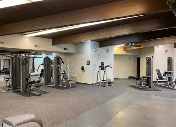 A gym with a variety of equipment including treadmills, weights, and exercise machines.