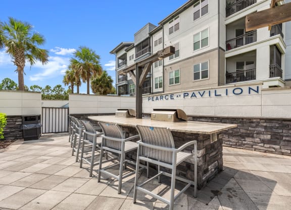 a patio with a bar and chairs in front of an apartment building at Pearce at Pavilion Luxury Apartments, Riverview, FL, Florida