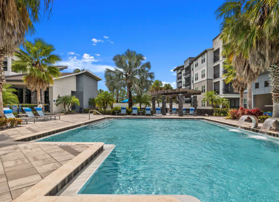a swimming pool with palm trees in front of an apartment building at Pavilion Luxury Apartments, Riverview, FL, Florida, 33578