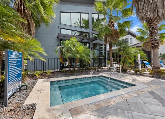a swimming pool in front of a building with palm trees at Pavilion Luxury Apartments, Riverview, 33578