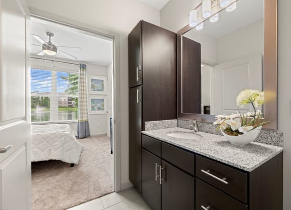a bathroom with dark cabinets and a vanity with a sink at Pearce at Pavilion Luxury Apartments, Florida