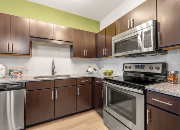 a kitchen with stainless steel appliances and wooden cabinets at Pearce at Pavilion Luxury Apartments, Riverview, Florida