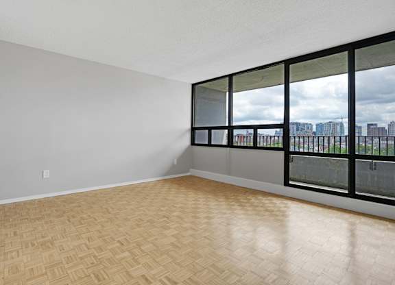 Empty room with wooden floor and large windows.