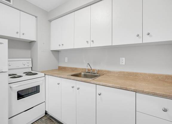 A kitchen with white cabinets and a wooden countertop.
