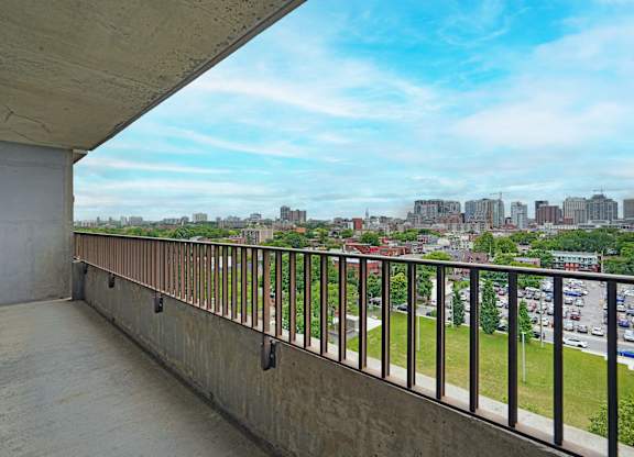 A balcony with a metal railing overlooks a cityscape.