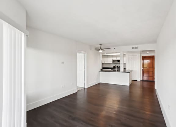 A spacious living room with faux wooden floors and white walls.