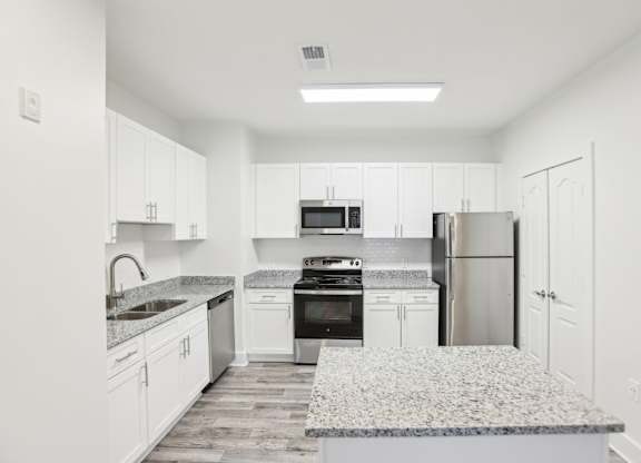 A kitchen with white cabinets and a granite countertop.