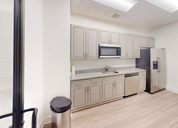 A kitchen with a refrigerator, microwave, and oven.