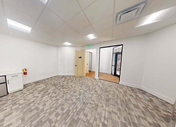 A room with a grey carpet and white walls.
