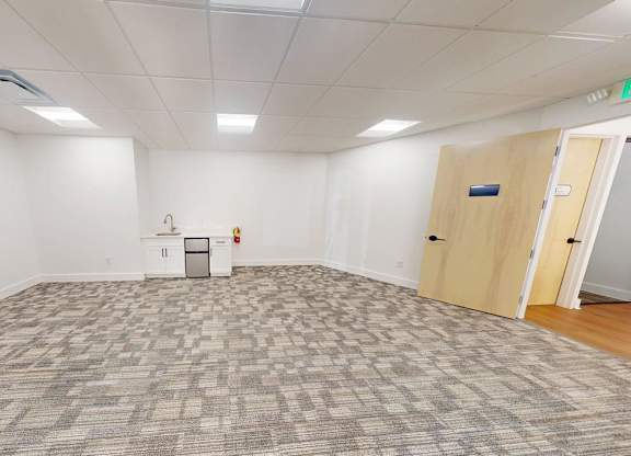 A room with a grey carpet and white walls.