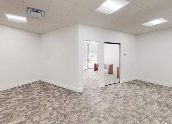 A room with a carpeted floor and a door on the right side.