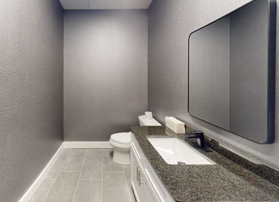 A bathroom with a toilet, sink, and mirror.