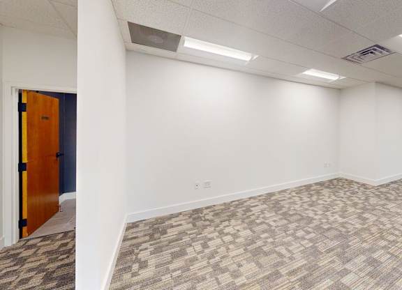 A room with a carpeted floor and a door on the left.