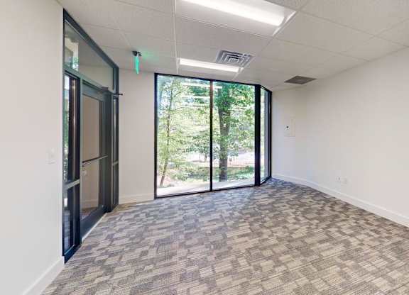 A room with a carpeted floor and a glass door leading outside.